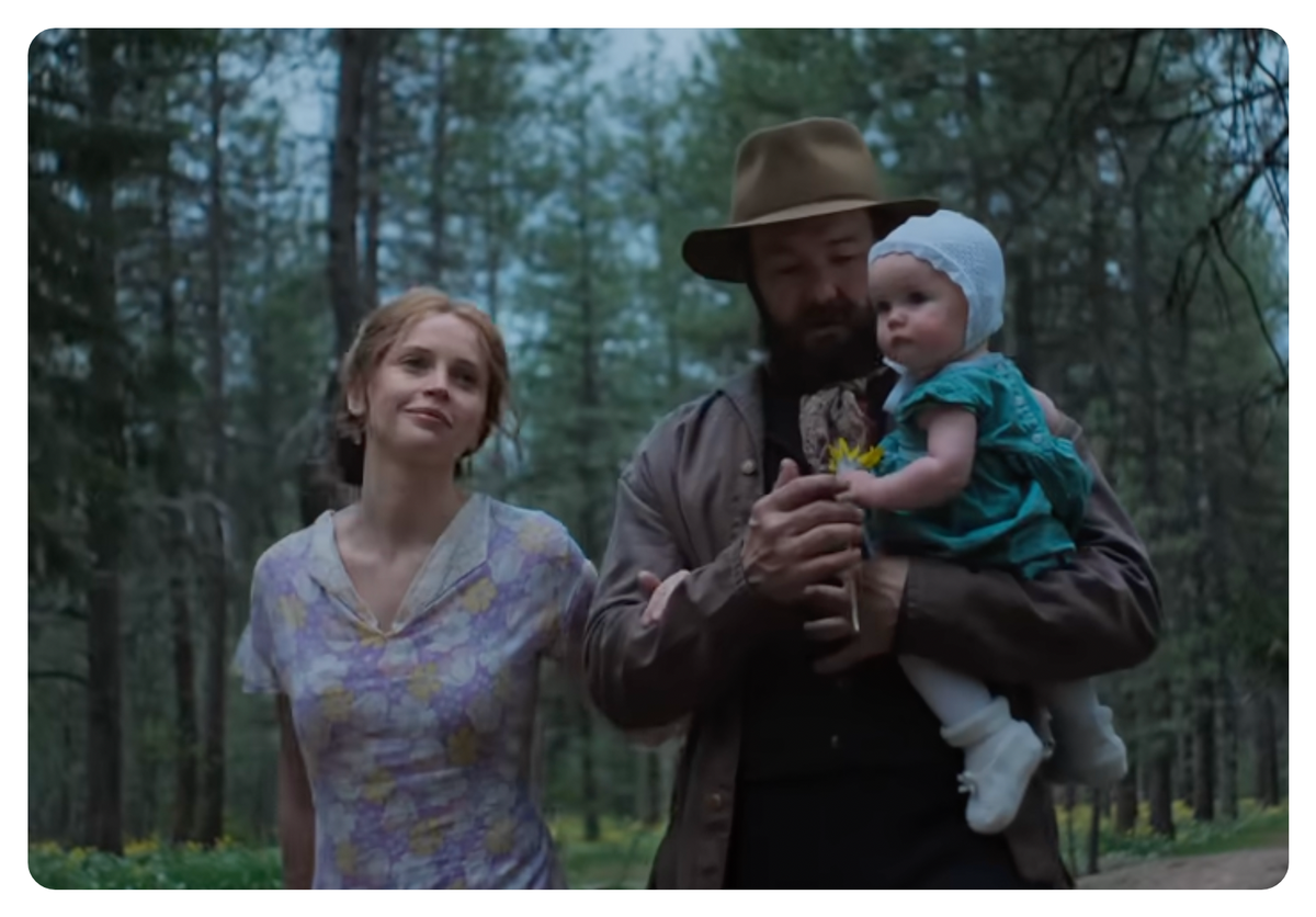 A woman, man, and baby in a still from Train Dreams.