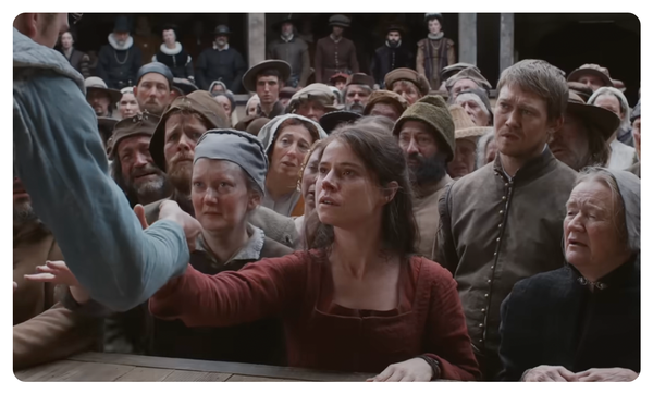 a woman in a theater audience reaches onto the stage to touch an actor